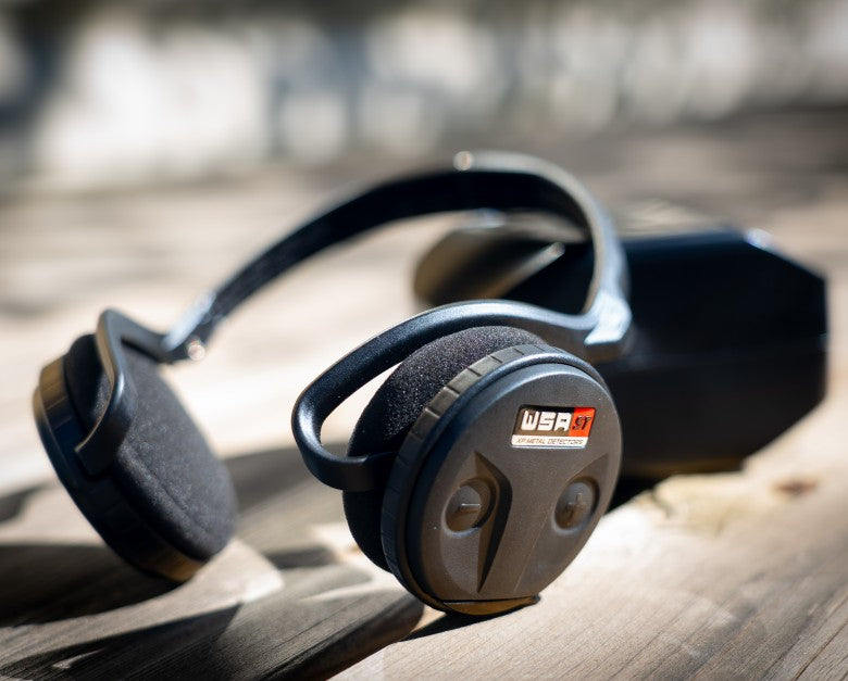 XP WSA-ST wireless headphones resting outdoors next to the remote control case